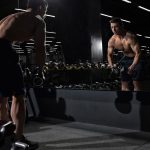 man carrying dumbbell standing in front of mirror